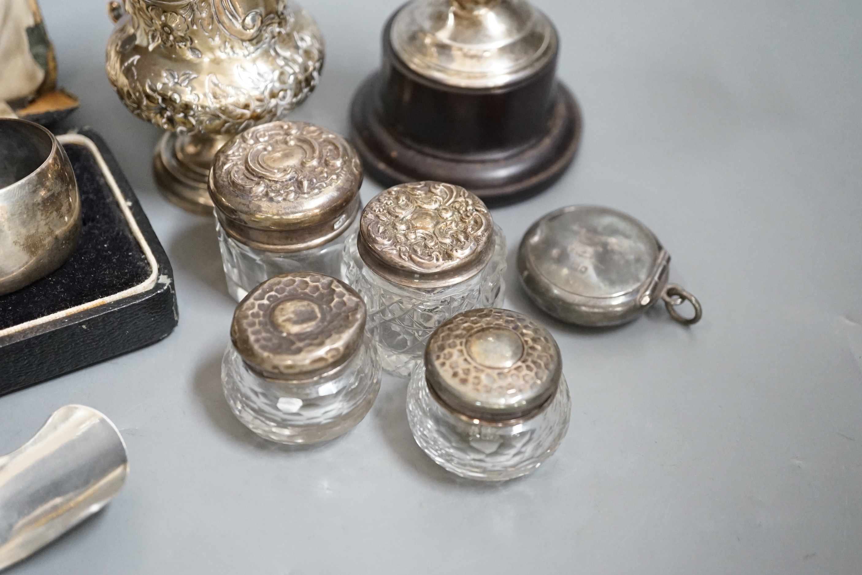 A Victorian repousse silver christening mug, Birmingham, 1861, 9.5cm, a cased pair of silver napkin rings, four assorted silver mounted toilet jars, a silver compact, small silver trophy cup and a silver caddy spoon.